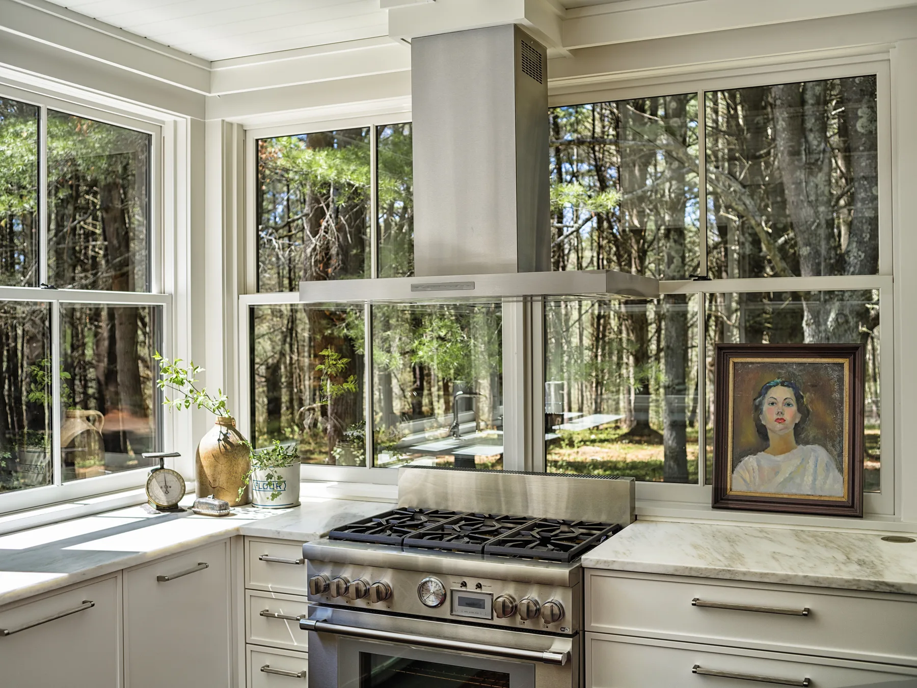 Sunlit kitchen with range and floor-to-ceiling windows looking out into Berkshire woods